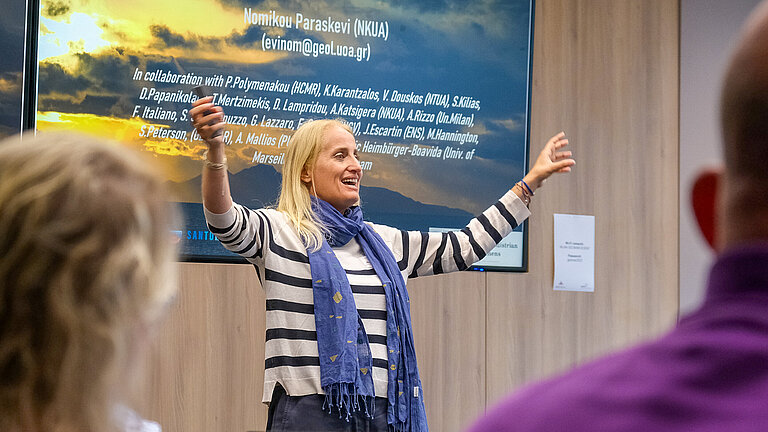 Eine blonde Frau hält begeistert eine Präsentation in einem Konferenzraum