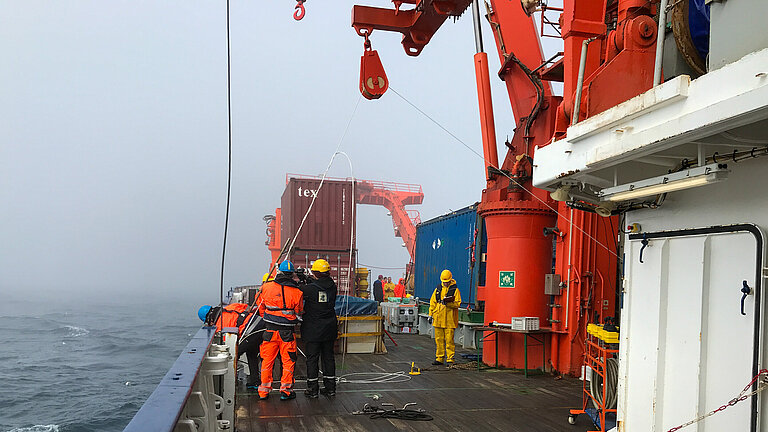 Ship's crew and researchers in yellow and orange-coloured work suits on a research vessel