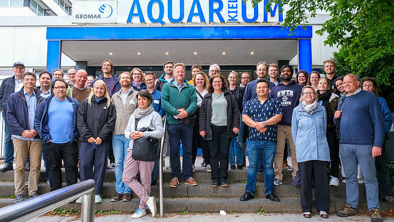 A group of 40 people on the steps in front of a public aquarium