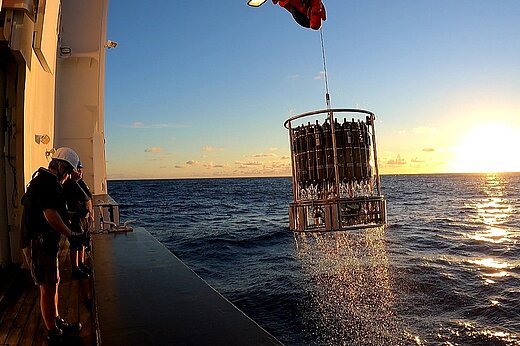 Ein Kranzwasserschöpfer wird bei Sonnenuntergang an Bord eines Forschungsschiffes gehievt