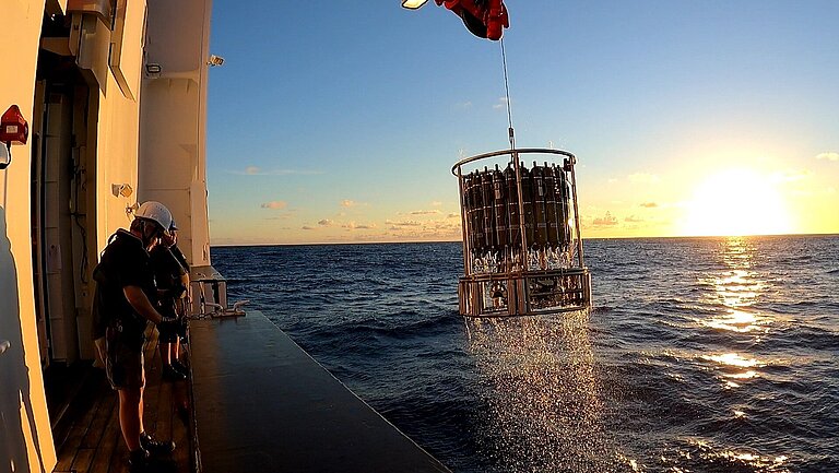 Ein Kranzwasserschöpfer wird bei Sonnenuntergang an Bord eines Forschungsschiffes gehievt