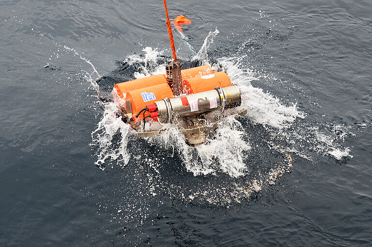 A small platform with orange-coloured cylinders splashes onto the surface of the sea