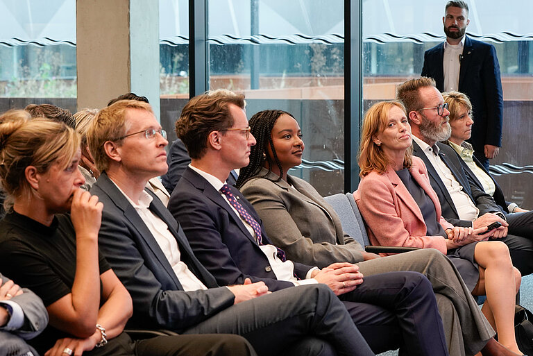 A row of politicians sits in a conference room