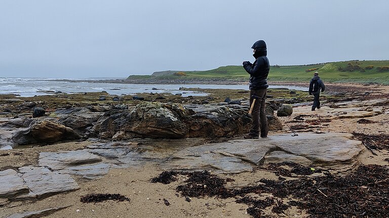 Person standing on carbon stones on the coast in Scotland